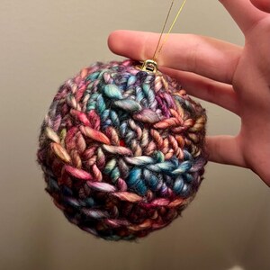 Pu&ograve; includere: Un ornamento natalizio lavorato a uncinetto colorato con un filo dorato per appenderlo.