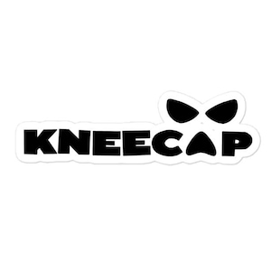 May include: A white sticker featuring the word "KNEECAP" in black, bold lettering. Above the text is a black graphic of two eye-like shapes. This sticker is designed for decorative purposes.