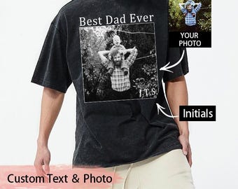 May include: Black t-shirt with a faded, vintage look. The shirt features a black and white photo of a person carrying a child on their shoulders, with the text "Best Dad Ever" above the photo and initials below. The shirt also has a small photo and initials section.