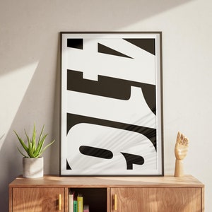 May include: A black and white framed print with the number "4" in large, bold, white letters. The print is hanging on a wall above a wooden cabinet.