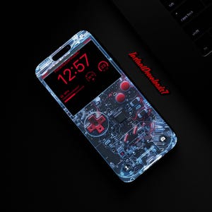 Puede incluir: Una funda transparente para teléfono con un diseño de placa de circuito y botones rojos. La pantalla del teléfono muestra un reloj digital y un icono de batería. El texto "Instant Downloads?" es visible en la pantalla.