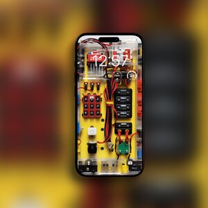 Puede incluir: Primer plano de la pantalla de un teléfono inteligente que muestra un fondo de pantalla personalizado con temática de LEGO. El fondo de pantalla presenta un reloj digital, una barra de progreso y un diseño de placa de circuito. El teléfono es negro con una funda transparente.