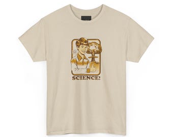 Könnte beinhalten: Beigefarbenes T-Shirt mit Retro-Grafik. Die Grafik zeigt einen lächelnden Jungen, der den Daumen hochhält, mit einer Atompilzwolke und dem Wort "SCIENCE!" in einem braunen Rahmen. Das T-Shirt hat einen Rundhalsausschnitt und kurze Ärmel.