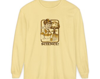 Op de afbeelding: Een lichtgeel shirt met lange mouwen met een retro-illustratie. De afbeelding toont een lachende persoon die een duim omhoog steekt naast een paddenstoelwolk en het woord "SCIENCE!" in vintage stijl.
