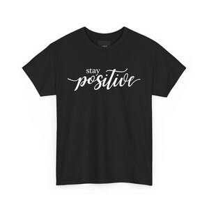 Könnte beinhalten: Schwarzes T-Shirt mit weißem Text in kursivschrift, der "stay positive" lautet.