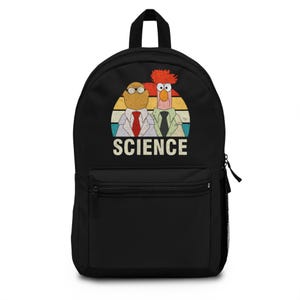 May include: Black backpack with a front pocket and a top handle. The backpack features a retro design with two cartoon characters in lab coats and the word "SCIENCE" in a vintage font, set against a sunset background.