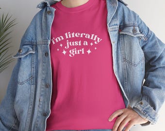 May include: A pink t-shirt with the text "I'm literally just a girl" in white with small white stars around the text.