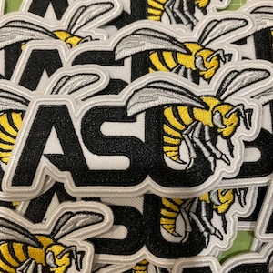 May include: A collection of embroidered patches featuring a yellow and black hornet insect graphic positioned above the bold black letters ASU. Each patch has a white stitched border and a detailed design of the insect with silver wings.