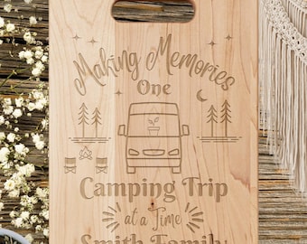 May include: A wooden cutting board with an engraved design of a camper van, trees, and a campfire. The text reads "Making Memories One Camping Trip at a Time Smith Family".