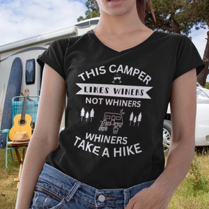 May include: Black v-neck t-shirt with white text that reads "This Camper Likes Winers Not Whiners Whiners Take A Hike". The text is surrounded by a white camper van graphic and pine trees.