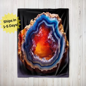May include: A close-up of a large, colorful agate geode with a deep orange center surrounded by concentric rings of blue, white, and brown. The geode is set against a black background.