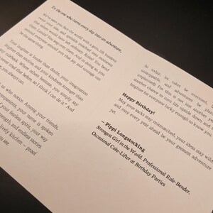 May include: A white greeting card with black text. The card's message includes birthday wishes and a quote from Pippi Longstocking. The card is designed to inspire and celebrate life's adventures. The card is on a dark surface.