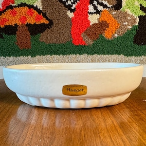 May include: White ceramic oval planter with a gold label that reads "COPYRIGHTED Haegar".