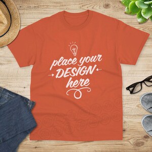 May include: A bright orange t-shirt with a white lightbulb graphic and the text "place your design here".