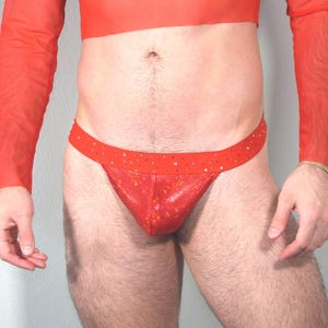 Puede incluir: Camiseta roja de manga larga de malla con ropa interior roja brillante de estilo tanga.