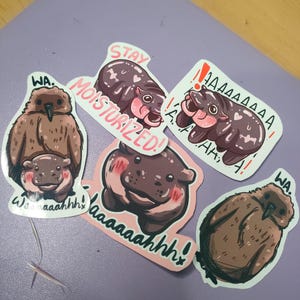 May include: Five stickers featuring cartoon hippos and birds. The stickers have different phrases written on them, including "Stay Moisturized!" and "Waaaaahhhh!"