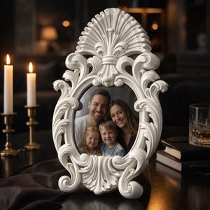 May include: An oval-shaped white picture frame featuring intricate, raised scrollwork and floral-inspired carvings along the border. The frame holds a photograph of a family consisting of two adults and two children, all smiling toward the camera.