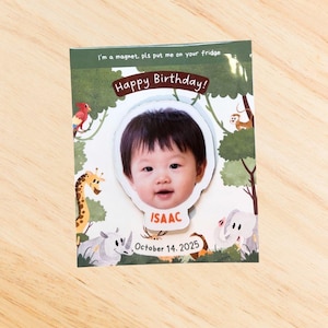 May include: A rectangular magnet featuring a baby's photo, framed by a jungle design. The magnet displays "Happy Birthday!" and "ISAAC, October 14, 2025." The text "I'm a magnet, pls put me on your fridge" is also present.