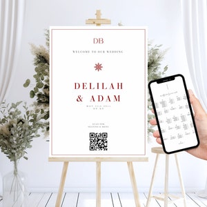 以下が含まれることがあります： 雪の結晶のグラフィックが描かれた、赤い文字で「DB 私たちの結婚式へようこそ」と書かれた白い結婚式のウェルカムサイン。テキストの下には「Delilah & Adam」と日付「May 11th, 2024」と「NY, NY」が書かれています。日付の下には「座席とメニューをスキャンしてください」とQRコードが書かれています。