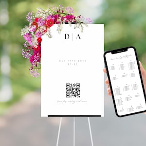 以下が含まれることがあります： 「D|A」のイニシャルと「MAY 11TH 20XX NY, NY」の日付が書かれた白いウェディングサイン。日付の下には、「Scan for seating and menu」というテキストが書かれた白黒のQRコードがあります。サインの左上隅には、ピンク、白、赤の花のフラワーアレンジメントがあります。