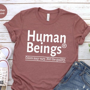 May include: A heather mauve t-shirt with the text "Human Beings®" in white. The text is followed by the phrase "Colors may vary. Not the quality."