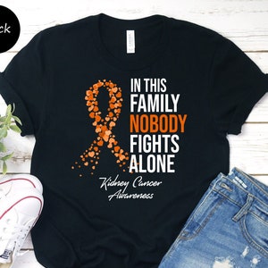 May include: Black t-shirt with an orange ribbon made of hearts and the text "In this family nobody fights alone. Kidney Cancer Awareness."