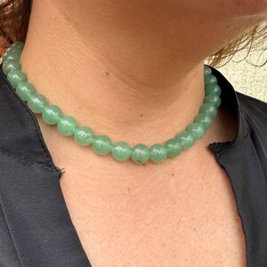 May include: A green gemstone necklace with round beads. The necklace is made of natural stones and is a beautiful piece of jewelry.