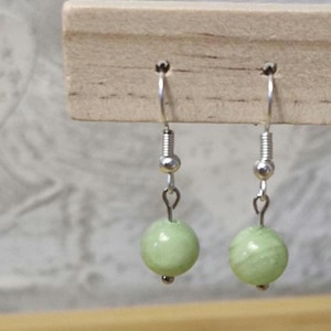 Peut inclure: Une paire de boucles d'oreilles en argent avec des perles rondes vert clair.