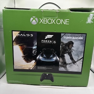 May include: Green Xbox One game console box with the Xbox logo and the words "XBOX ONE". The box features game covers for Halo 5, Forza Motorsport 6, and Rise of the Tomb Raider. A black controller is at the bottom.