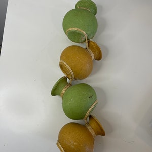 May include: A decorative hanging ornament with four spherical, gourd-shaped pieces in alternating green and tan hues. Each piece is wrapped with twine and has a flared top. A rustic, handcrafted design.