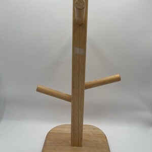 May include: A wooden mug tree with a rectangular base and a central vertical post. Two horizontal arms extend from the post, and a peg is at the top. The natural wood finish gives it a rustic look.