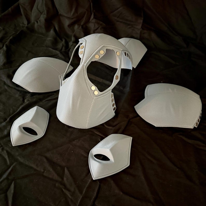 May include: A set of five white, textured, foam pieces for a costume. The pieces include a headpiece, two shoulder pads, and two smaller pieces.