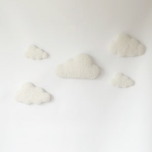 May include: Five white fluffy cloud-shaped wall decorations on a white background.