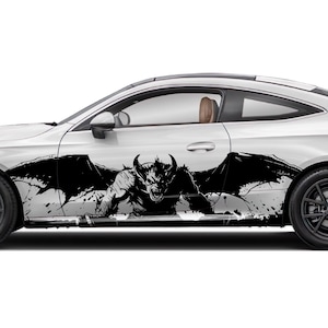 May include: White coupe car featuring a black demon graphic with wings and horns. The design is on the side of the car, with a splatter effect. The car has dark grey wheels and a brown interior.