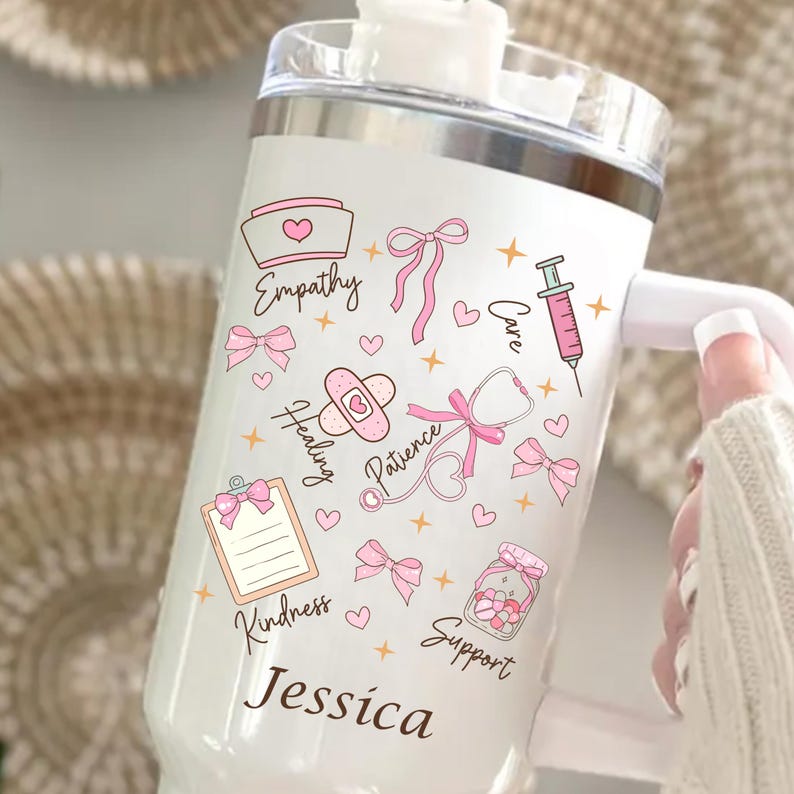 Personalized nurse tumbler with name, white 40oz insulated travel mug featuring pink nursing icons, bows, hearts and stethoscope design.
