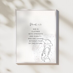 May include: A framed print with the text "Proverbs 31:25" and the quote "She is clothed with strength and dignity, and she laughs without fear of the future." The print features a minimalist line drawing of a woman wearing a hat.