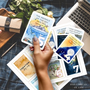 Puede incluir: Un juego de cartas ilustradas coloridas con fondos de acuarela. Las cartas presentan texto del libro de G&eacute;nesis en la Biblia. Las cartas est&aacute;n numeradas del 1 al 7 e incluyen frases como "Los animales del cielo y del mar" y "El sol, la luna y las estrellas".