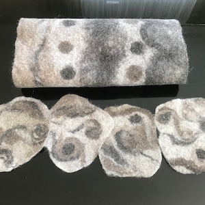 May include: Set of five grey and white felted coasters with a marbled pattern. The coasters are round and have a slightly irregular shape.