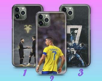 Puede incluir: Tres fundas de teléfono diferentes con imágenes de famosos jugadores de fútbol. La primera funda tiene una imagen en blanco y negro de dos jugadores de fútbol dándose la mano con un símbolo de cabra en el centro superior. La segunda funda tiene una imagen amarilla y azul de un jugador de fútbol con una camiseta amarilla con el nombre "RONALDO" en la espalda. La tercera funda tiene una imagen en blanco y negro de un jugador de fútbol pateando un balón de fútbol con el número "7" en el fondo.