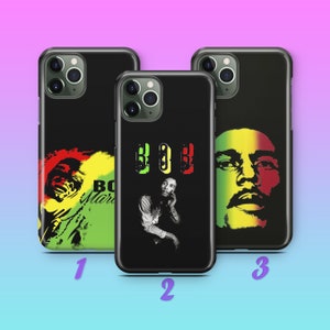 Puede incluir: Tres fundas de teléfono negras con diferentes diseños con Bob Marley. La primera funda tiene un fondo verde, amarillo y rojo con un retrato de Bob Marley. La segunda funda tiene un fondo negro con un retrato de Bob Marley y la palabra "BO$$" en verde, amarillo y rojo. La tercera funda tiene un fondo verde, amarillo y rojo con un retrato de Bob Marley.