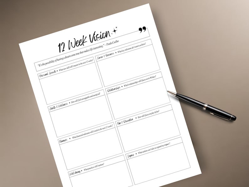 May include: A white paper titled "12 Week Vision" with fillable sections for personal goals, career, relationships, and more. A black pen rests on the paper, ready for use. The paper has a quote at the top.