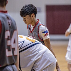 May include: Three basketball players in a game, one player is wearing a grey jersey with a red and white stripe and a Philippine flag patch on the right shoulder, another player is wearing a white jersey with a blue and yellow stripe, and the third player is wearing a grey jersey with a red and white stripe and the number 34 on the front.