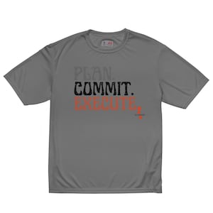 May include: Gray athletic t-shirt with the words "PLAN. COMMIT. EXECUTE." in a bold, stylized font. The word "EXECUTE" is in orange. The shirt has a crew neck and short sleeves. The brand logo is visible on the upper back.