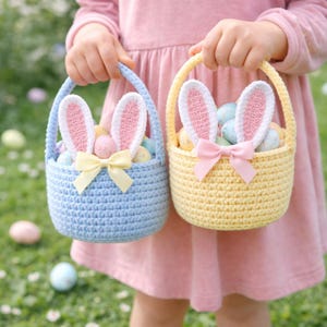 May include: Two crochet Easter baskets, one light blue and one yellow, are held by a person. Each basket has a handle, bunny ears, and a bow. The baskets are filled with colorful Easter eggs, perfect for an Easter egg hunt.