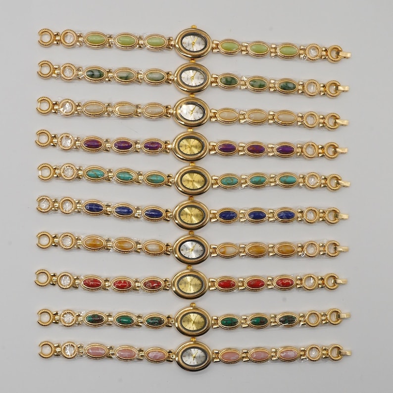 Puede incluir: Una colecci&oacute;n de relojes de pulsera dorados con esferas ovaladas y correas adornadas con piedras preciosas de colores. Las esferas del reloj muestran la hora. Las piedras preciosas son de varios colores, incluyendo verde, azul, rojo y rosa.