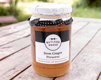 Puede incluir: Un tarro de vidrio de conserva de jengibre con una etiqueta en blanco y negro que dice "Butler's Grove Stem Ginger Preserve Provisions of distinction".