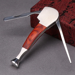 May include: A multi-tool pipe cleaning kit with a wooden handle and a silver metal head. The tool has a tamper, a poker, and a scraper.