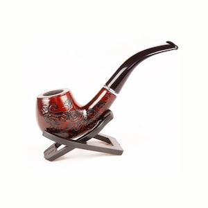 May include: A red wooden pipe with a black stem and intricate floral carvings. The pipe is resting on a black wooden stand.