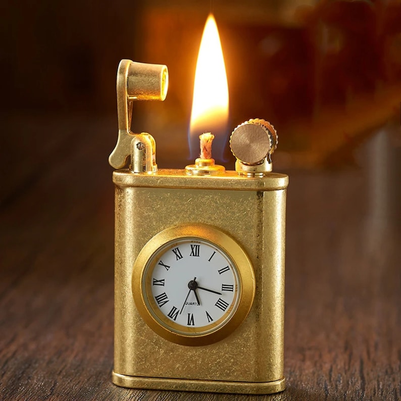 May include: A gold-toned lighter with a built-in clock. The lighter is lit and the flame is visible. The clock face has Roman numerals and says "QUARTZ" at the bottom.