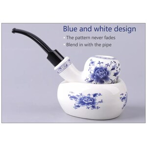 May include: A white ceramic pipe with a blue and white floral design. The pipe has a black stem and rests on a matching ceramic stand.